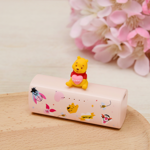 Power bank with cartoon characters and a small figurine on top, set against a light background with pink flowers.